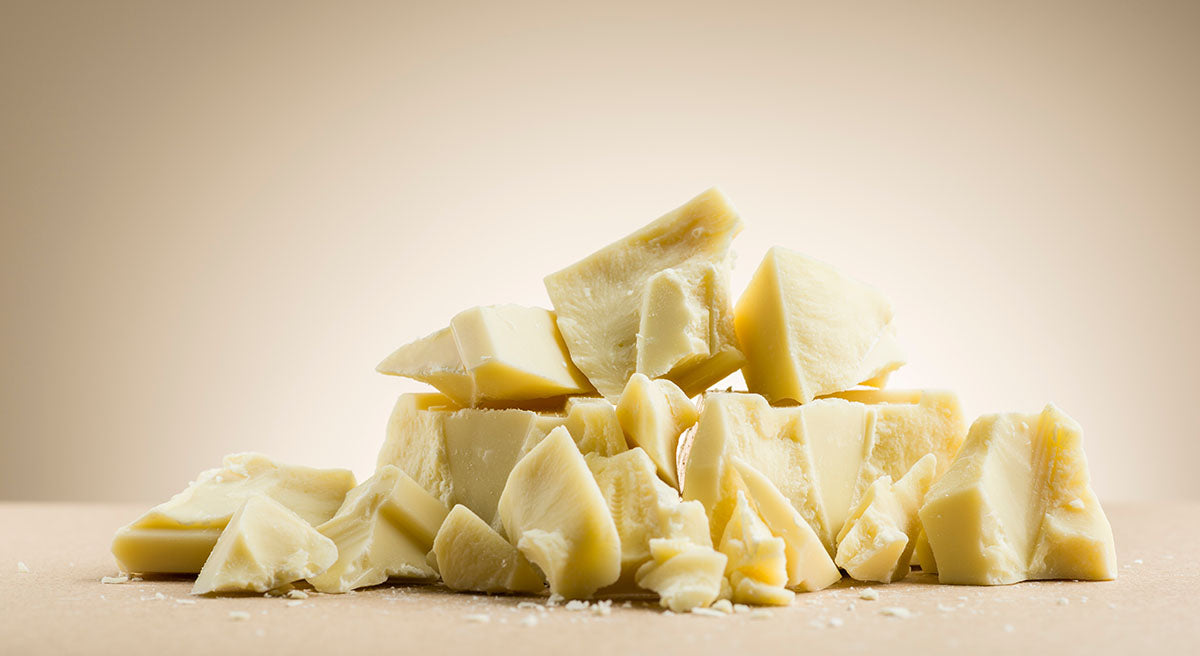 A pile of crumbled white chocolate in front of a cream background.