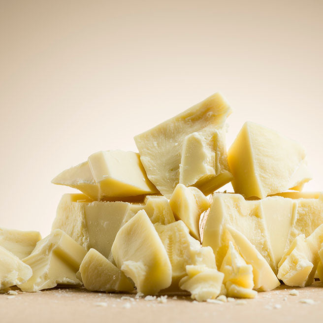 A pile of crumbled white chocolate in front of a cream background.